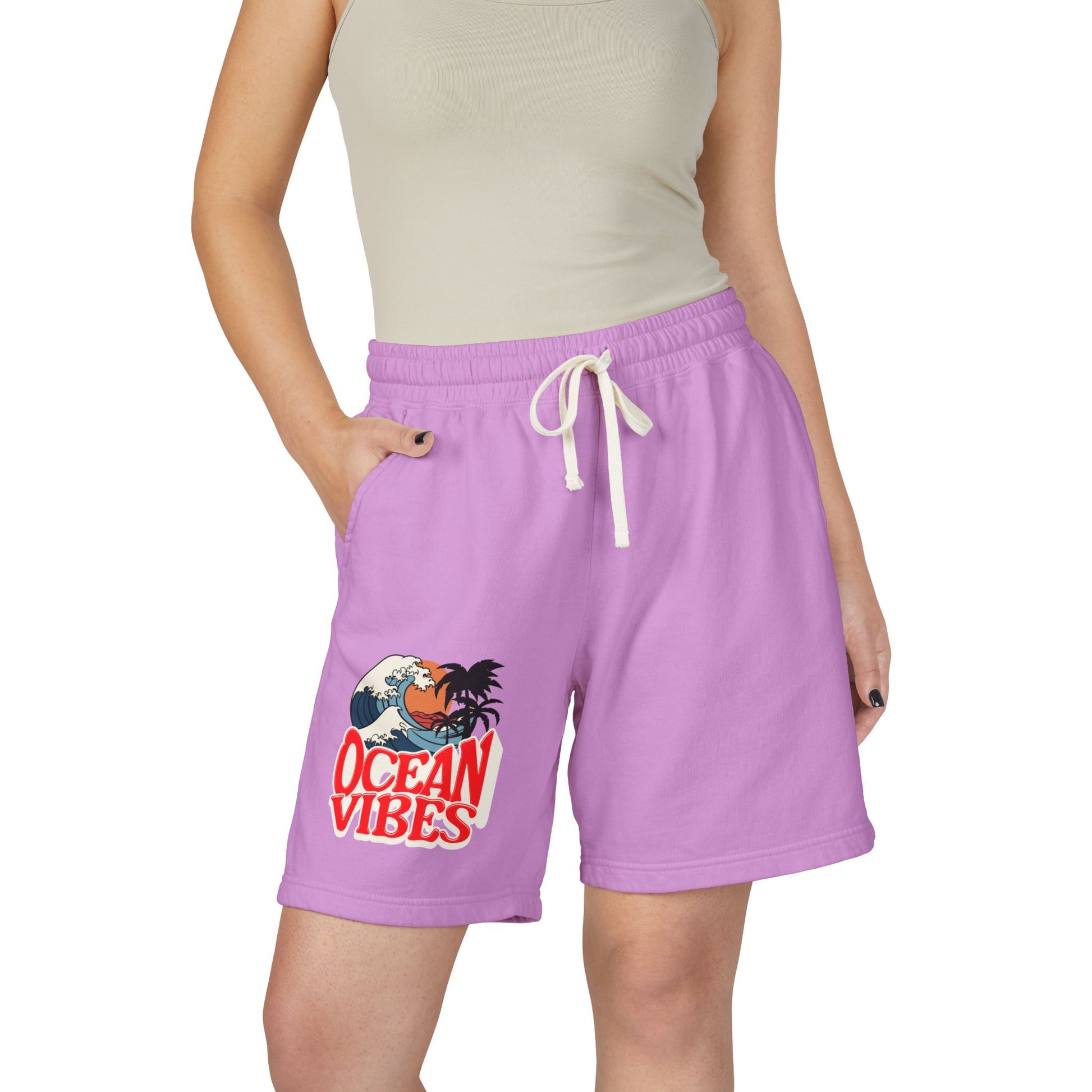 A model wearing lavender purple drawstring shorts with a 'Ocean Vibes' graphic on the left leg, paired with a beige ribbed tank top against a plain white background. Unique Lightweight Fleece Sweat Shorts in Ocean Vibes Graphic Shop Lightweight Fleece Sweat Shorts in Ocean Vibes for breezy comfort, relaxed style, and an easygoing summer-ready look all day. Refresh your casual rotation with Lightweight Fleece Sweat Shorts in Ocean Vibes—soft, versatile, and ready for sunny days by the shore.