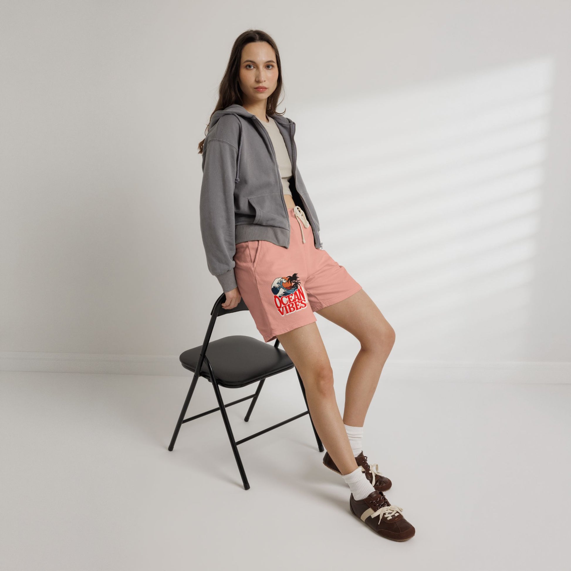 Woman wearing a gray hoodie and pink shorts with a design, standing next to a black chair on a white background. Unique Lightweight Fleece Sweat Shorts in Ocean Vibes Graphic Shop Lightweight Fleece Sweat Shorts in Ocean Vibes for breezy comfort, relaxed style, and an easygoing summer-ready look all day. Refresh your casual rotation with Lightweight Fleece Sweat Shorts in Ocean Vibes—soft, versatile, and ready for sunny days by the shore. Buy Lightweight Fleece Sweat Shorts in Ocean Vibes.