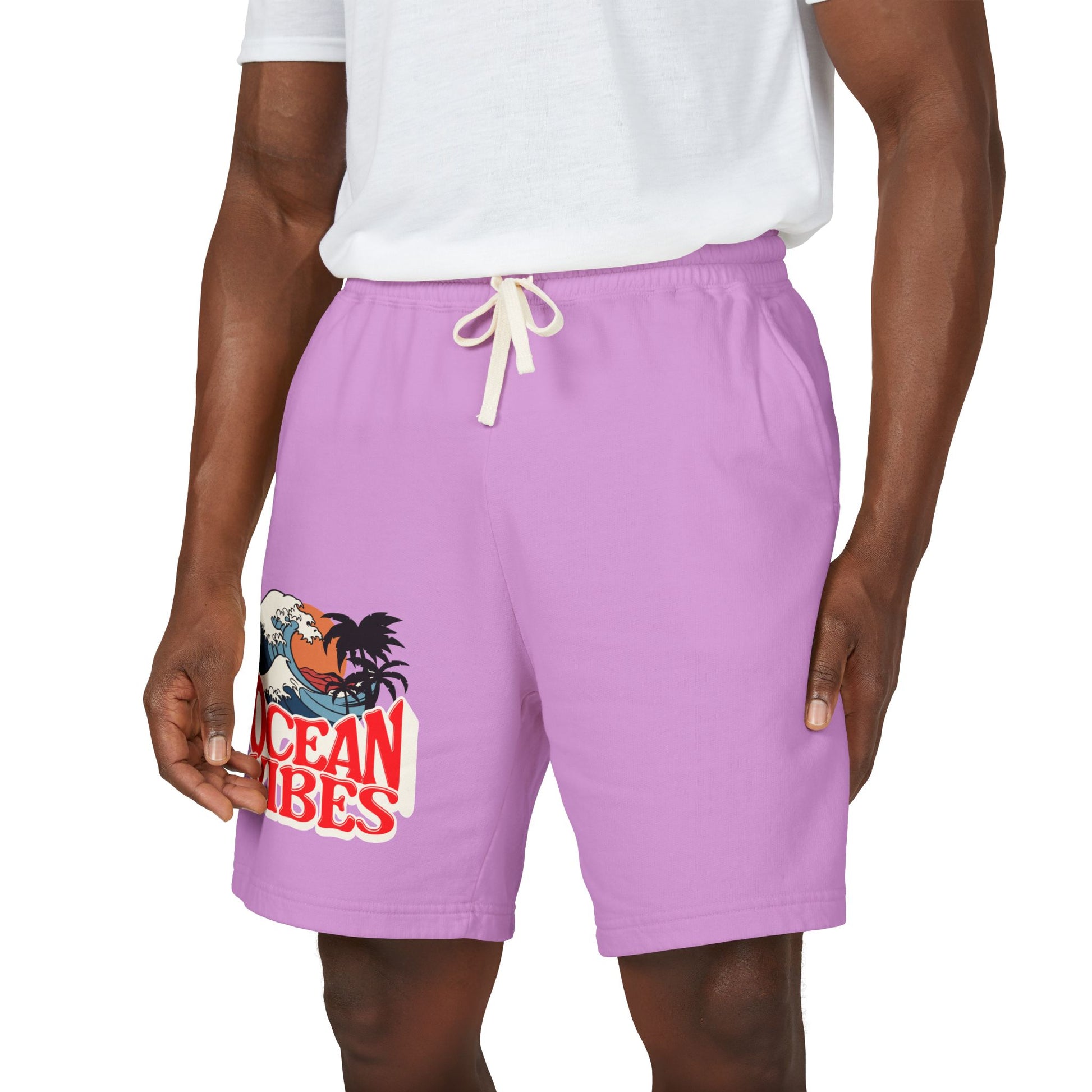 A person wearing lavender-purple drawstring shorts with a graphic print on the left leg that reads 'Ocean Vibes' with a rooster and wave illustration, paired with a white t-shirt against a plain white background. Unique Lightweight Fleece Sweat Shorts in Ocean Vibes Graphic Shop Lightweight Fleece Sweat Shorts in Ocean Vibes for breezy comfort, relaxed style, and an easygoing summer-ready look all day. Refresh your casual rotation with Lightweight Fleece Sweat Shorts in Ocean Vibes—soft, versatile.