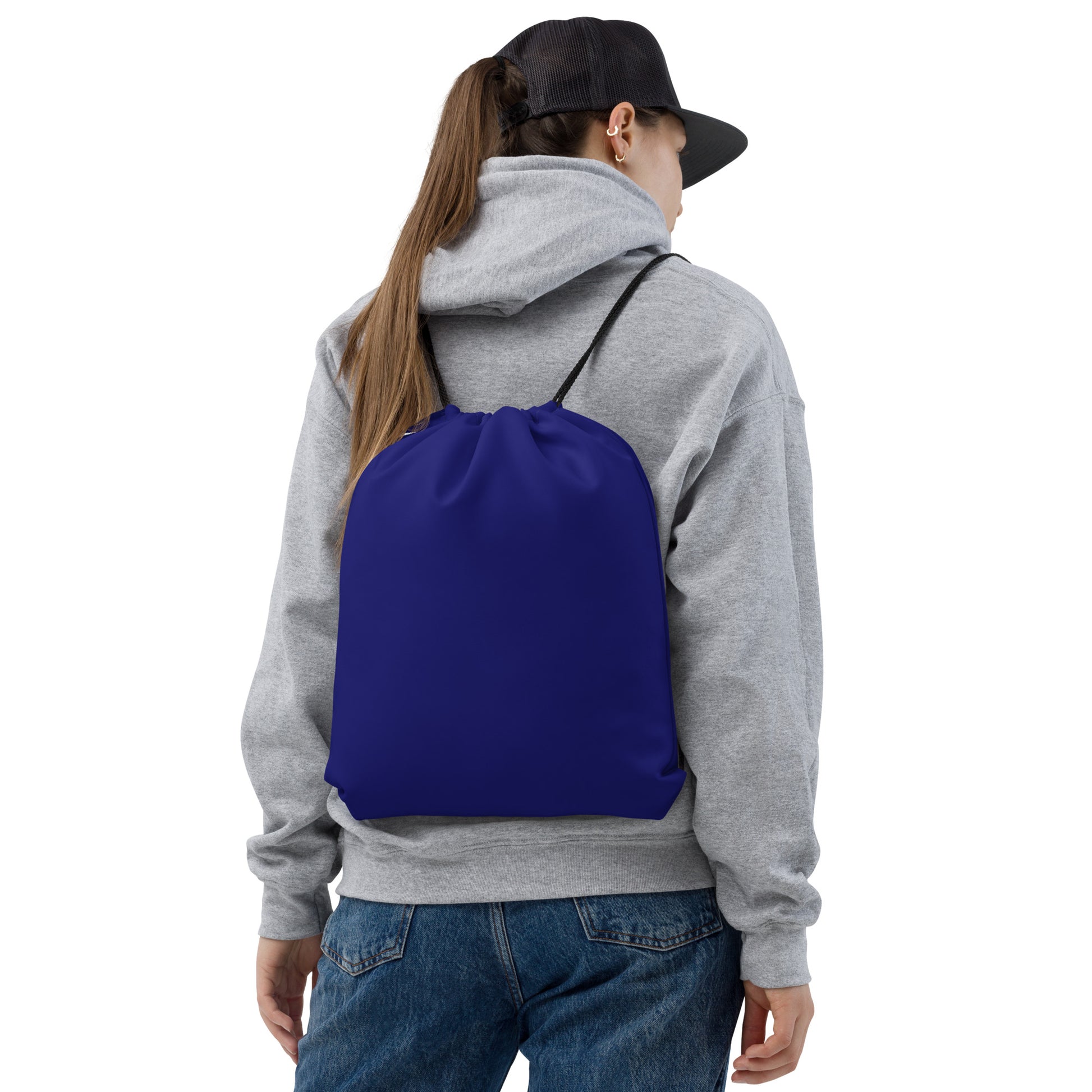 A person shown from the back wearing a plain royal blue drawstring backpack over a gray hoodie and blue jeans, against a clean white studio background. Compact Bold Minimalist Solid Midnight Blue Drawstring Bag