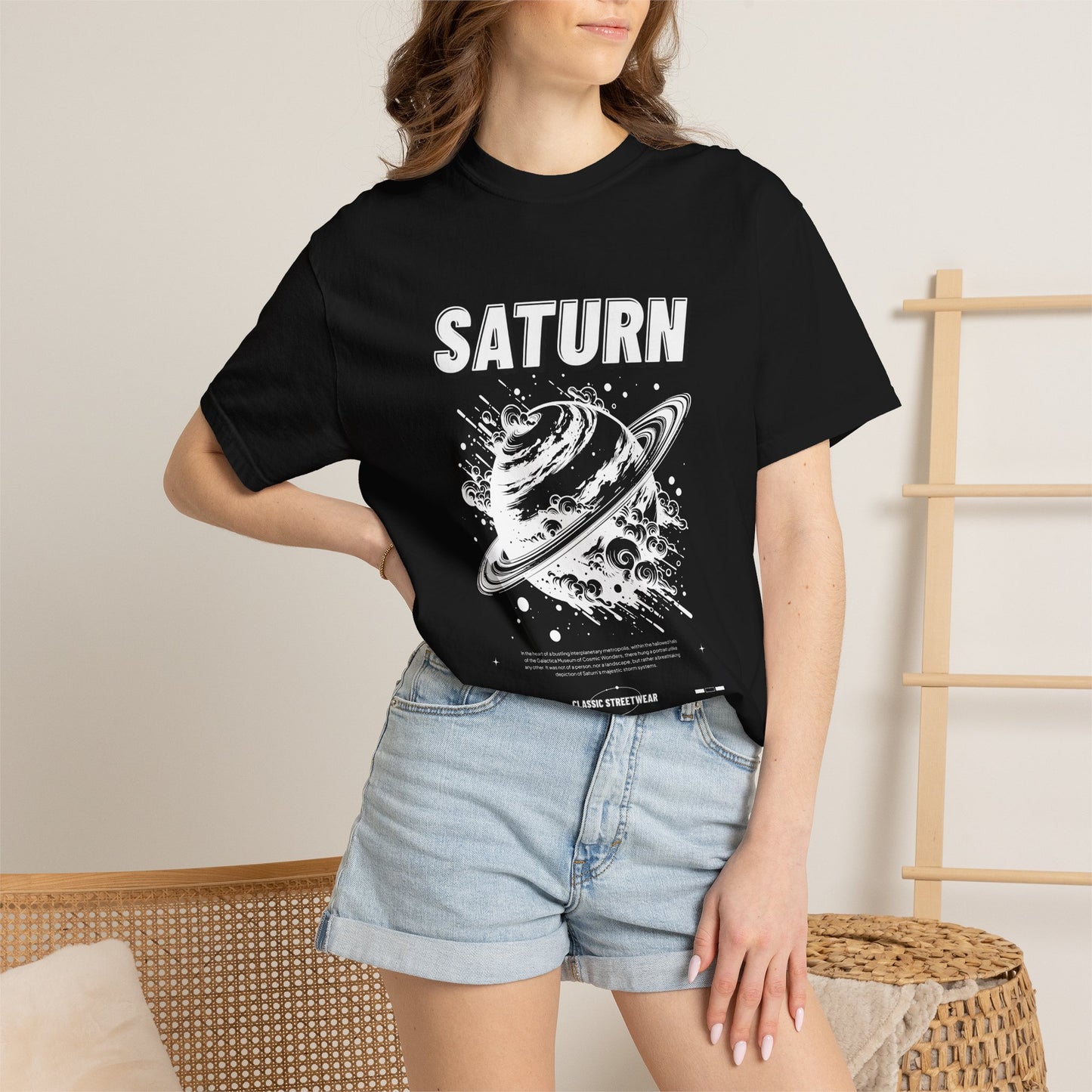 A woman wearing a black graphic t-shirt with a green and beige 'RUIN' character print, paired with light blue denim shorts, standing in a brightly lit indoor setting.