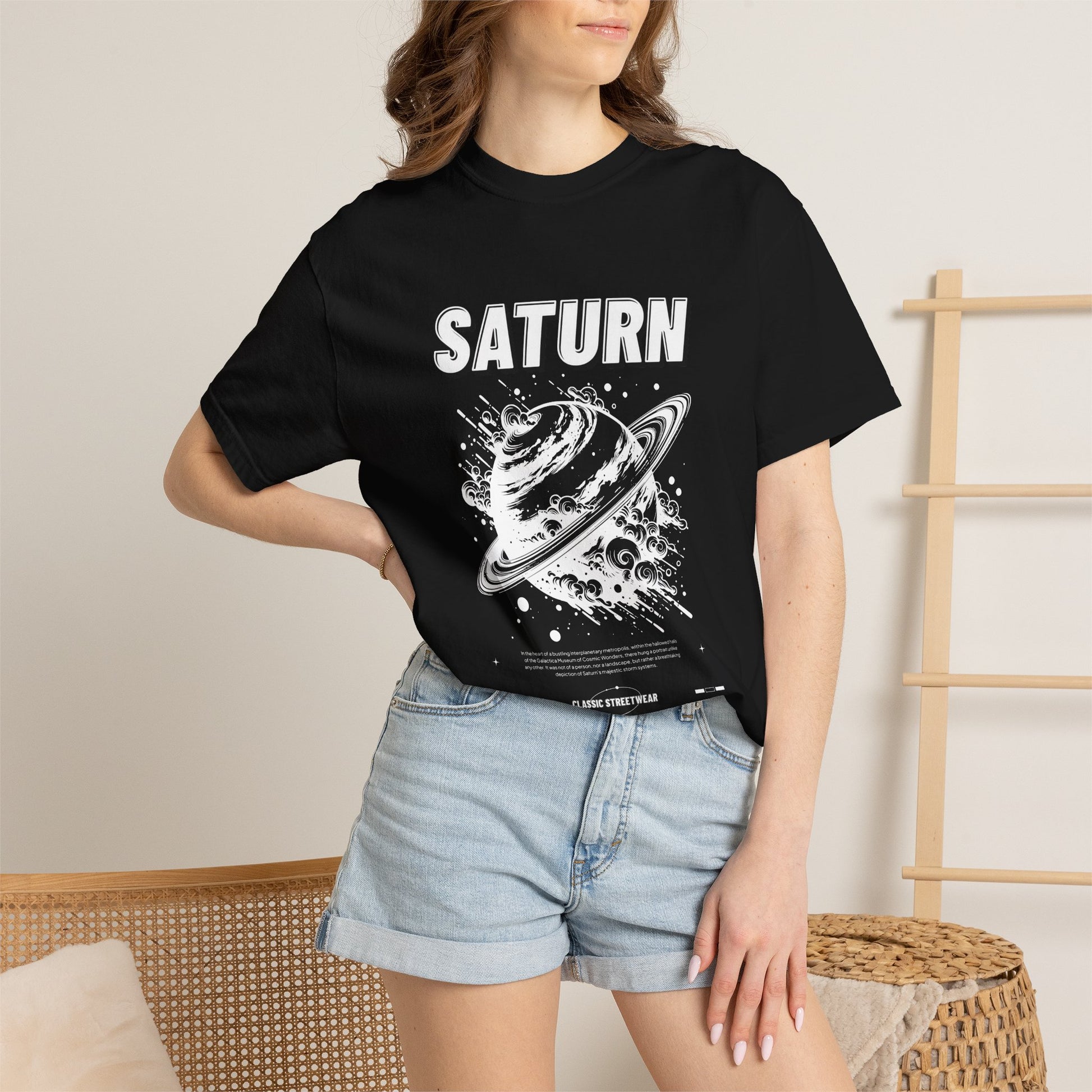 A woman wearing a black graphic t-shirt with a green and beige 'RUIN' character print, paired with light blue denim shorts, standing in a brightly lit indoor setting.