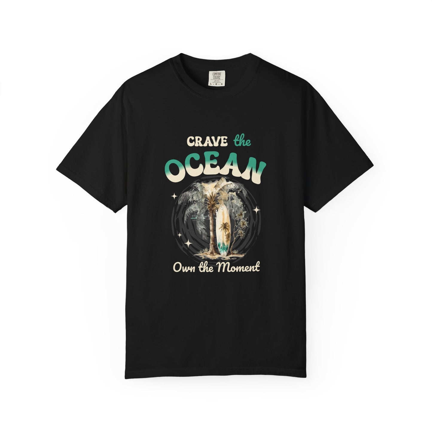 A black short-sleeve crewneck t-shirt with a graphic on the front that reads 'Crave the OCEAN Own the Moment' in stylized teal and white lettering, surrounding a central illustration of a surfer on a board. Crave the Ocean Own the Moment Graphic T-Shirt for Casual Wear