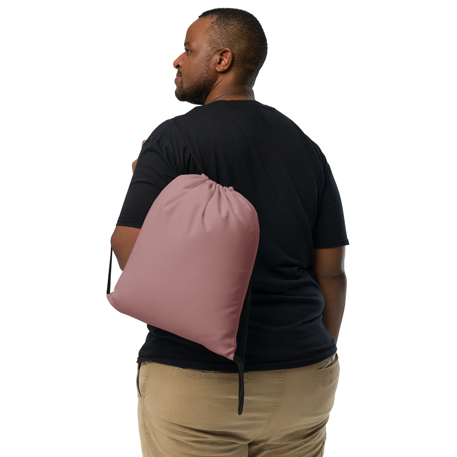 A man wearing a black t-shirt and khaki pants is shown from the back, carrying a dusty rose drawstring bag over his shoulder against a solid white background. Simple Minimalist Solid Rosy Brown Durable Drawstring Bag