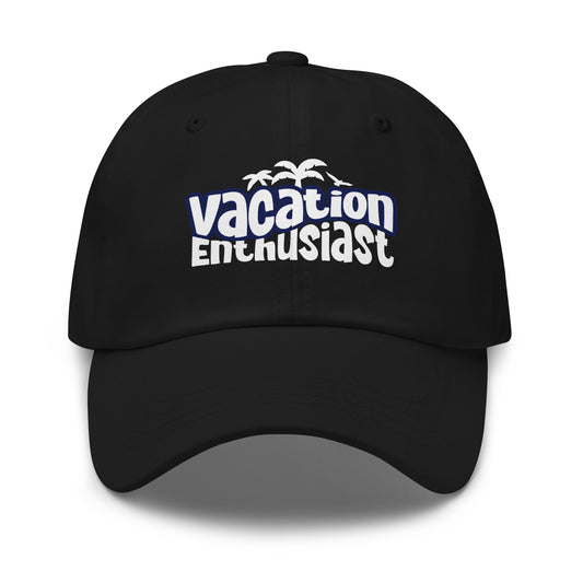 A black baseball cap with a curved brim, featuring a white and blue graphic on the front that reads 'vacation Enthusiast' with small palm tree silhouettes above the text, shown on a white background. Vacation Enthusiast Bold Graphic Classic Dad Cap