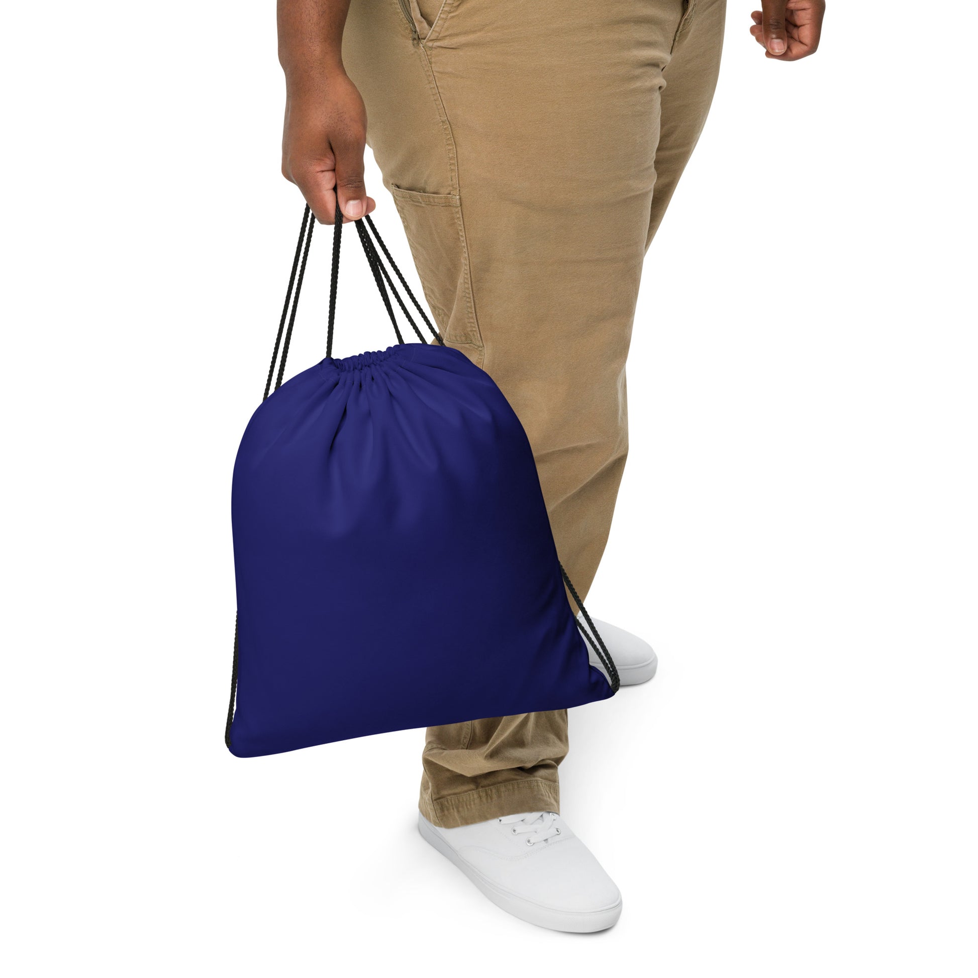 A person wearing khaki pants and white sneakers holds a royal blue drawstring bag against a plain white background. Versatile Bold Minimalist Solid Midnight Blue Drawstring Bag