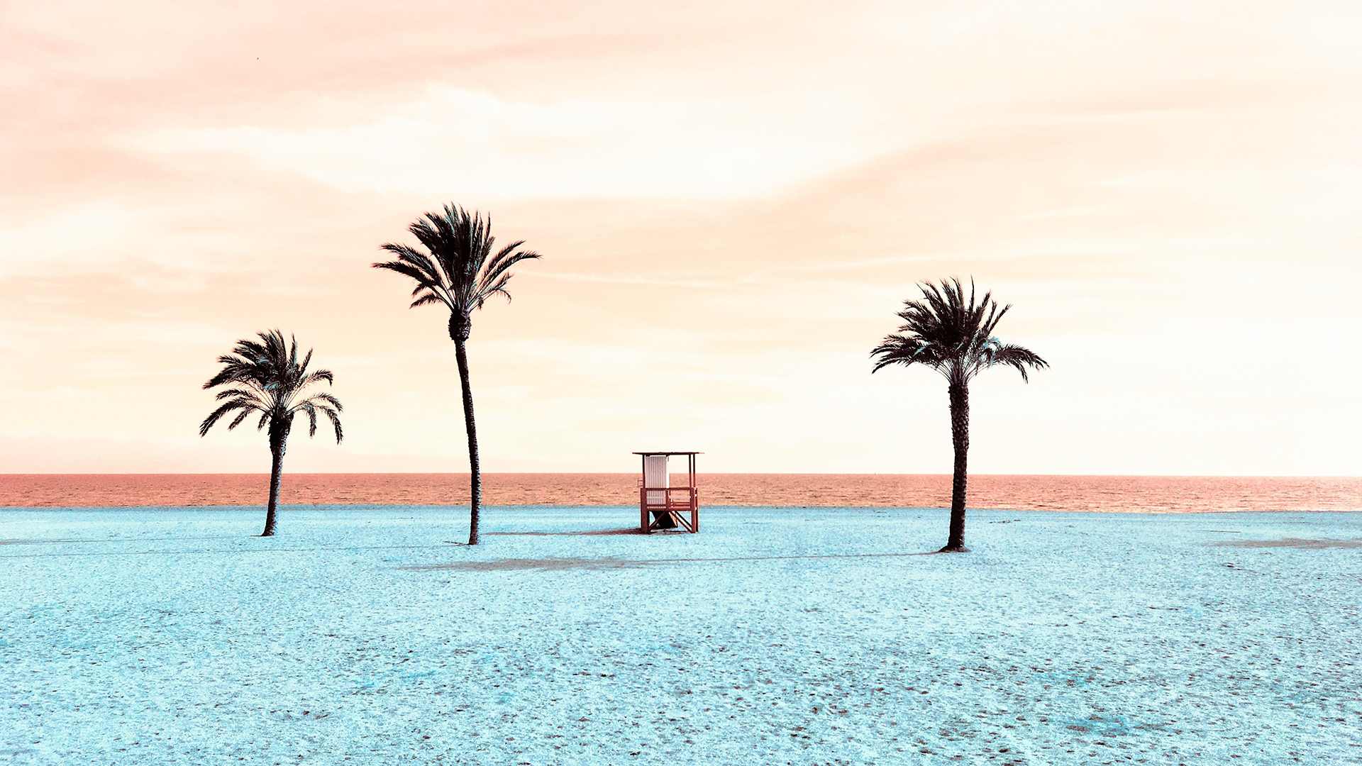 Three palm trees and a lifeguard stand on a beach with clear blue water and a pink sky.